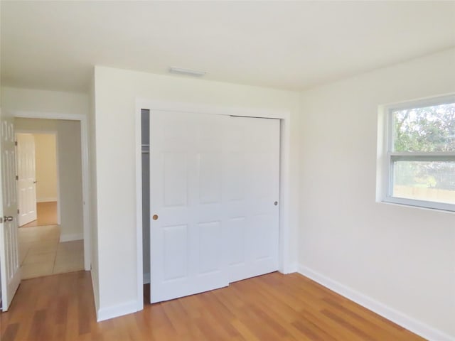 unfurnished bedroom with a closet, light wood-style flooring, and baseboards