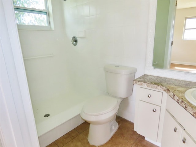 full bath featuring toilet, tile patterned flooring, tiled shower, and vanity