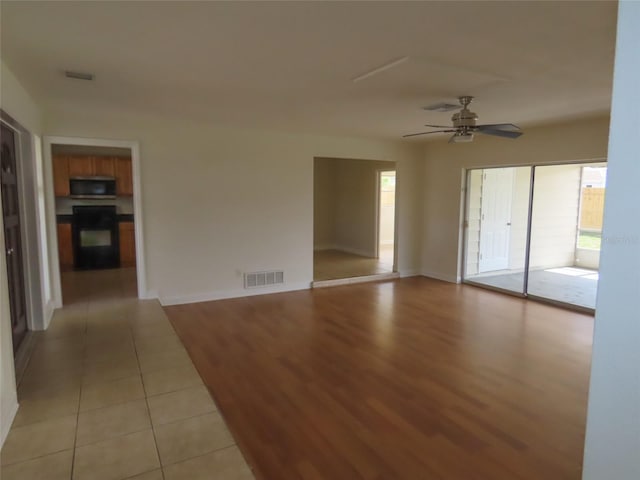 spare room with baseboards, light wood-style flooring, visible vents, and a ceiling fan