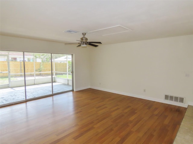 empty room featuring ceiling fan, wood finished floors, visible vents, and baseboards