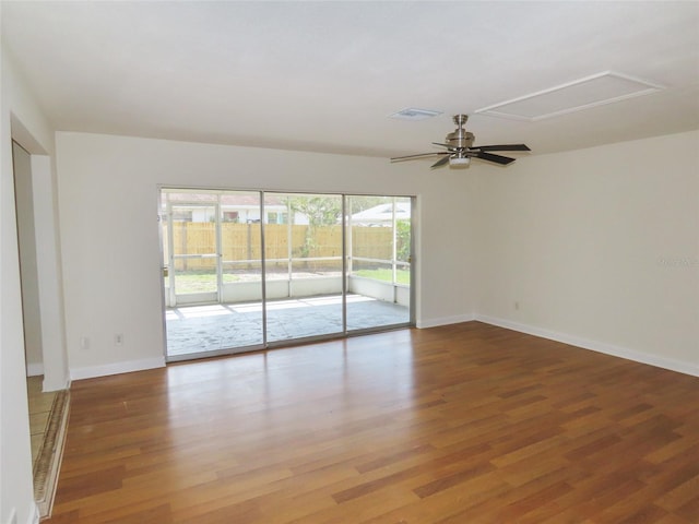 unfurnished room featuring attic access, wood finished floors, visible vents, and baseboards