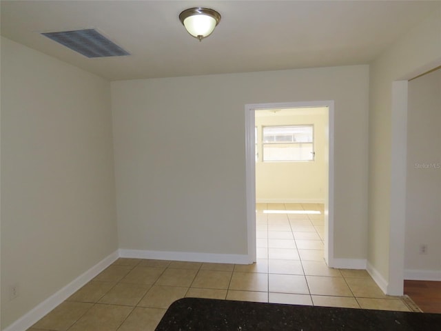 empty room featuring visible vents, baseboards, and light tile patterned flooring