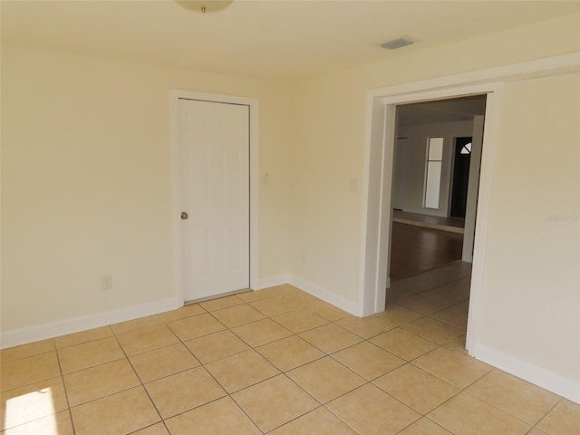 unfurnished room with light tile patterned flooring, visible vents, and baseboards