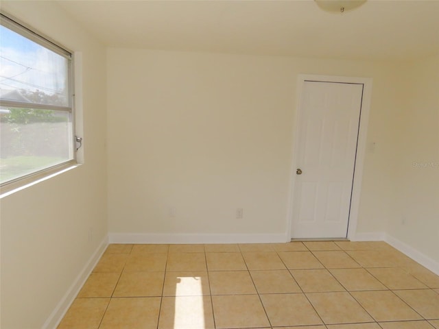 spare room with baseboards and light tile patterned flooring