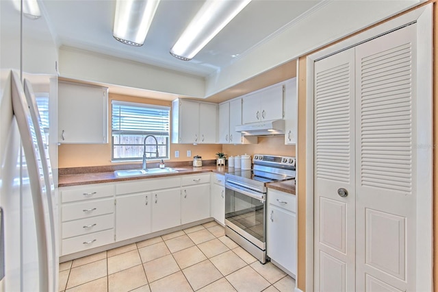 kitchen featuring light tile patterned floors, freestanding refrigerator, stainless steel range with electric cooktop, under cabinet range hood, and a sink