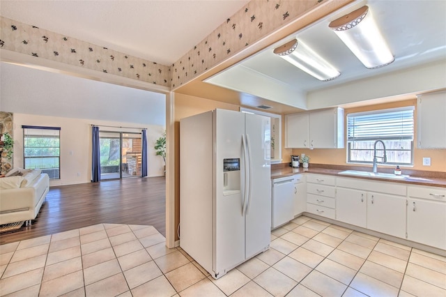 kitchen featuring white appliances, light tile patterned floors, open floor plan, and a sink