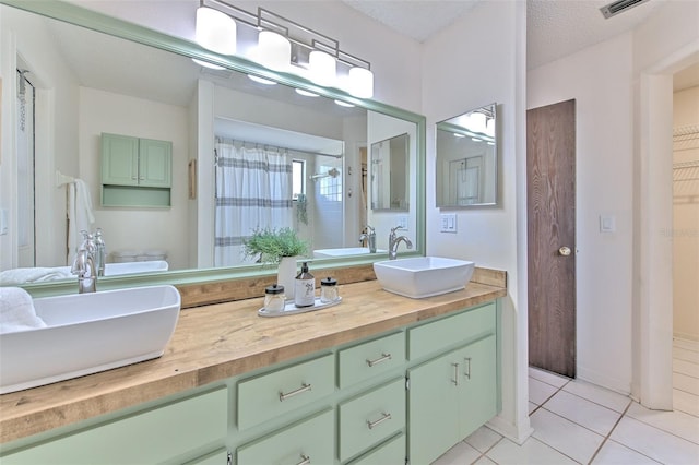 full bath with a textured ceiling, a shower with shower curtain, tile patterned flooring, and a sink