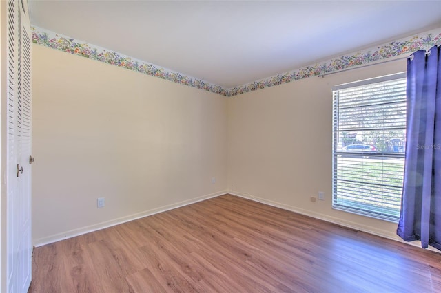 unfurnished room with a wealth of natural light, baseboards, and wood finished floors