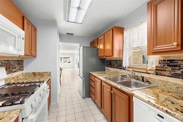 kitchen with a healthy amount of sunlight, white appliances, visible vents, and a sink