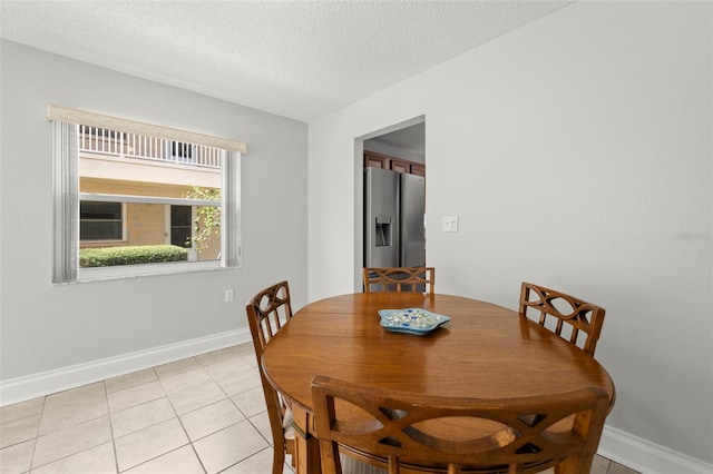 dining room with light tile patterned floors, a textured ceiling, and baseboards