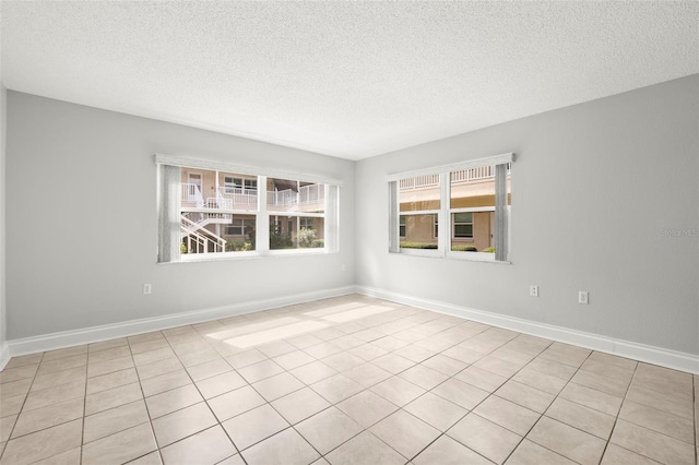 empty room featuring a textured ceiling and baseboards