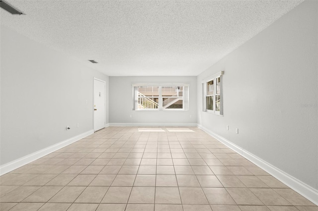 spare room featuring baseboards, visible vents, and a textured ceiling