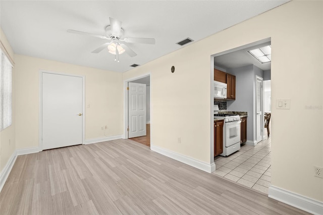 interior space featuring a ceiling fan, visible vents, and light wood-style floors