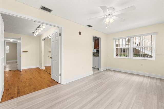 unfurnished room featuring ceiling fan, light wood-style flooring, visible vents, and baseboards