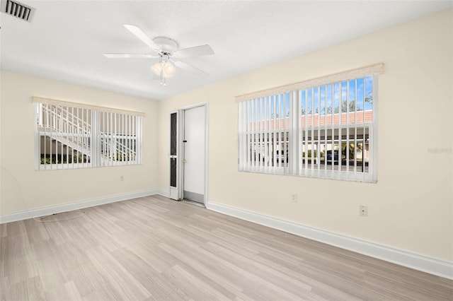 spare room with ceiling fan, wood finished floors, visible vents, and baseboards