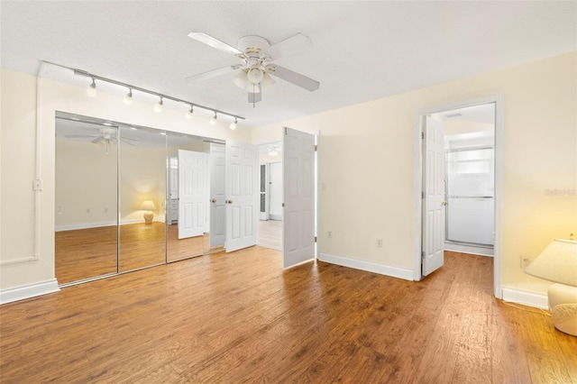 unfurnished bedroom with ceiling fan, a closet, wood finished floors, and baseboards