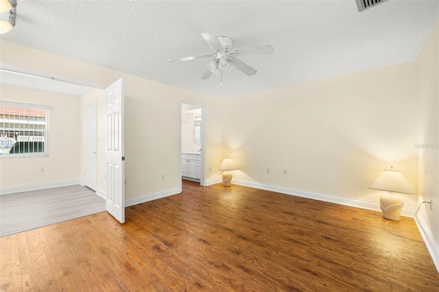 empty room featuring visible vents, a ceiling fan, a textured ceiling, wood finished floors, and baseboards