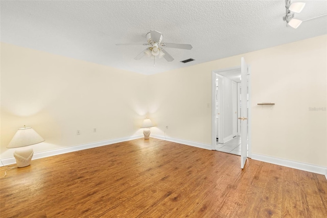 spare room featuring visible vents, ceiling fan, a textured ceiling, wood finished floors, and baseboards