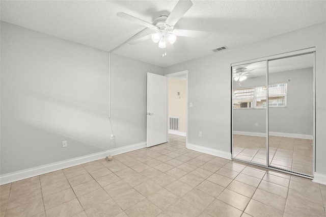 unfurnished bedroom featuring a textured ceiling, a closet, tile patterned flooring, and visible vents