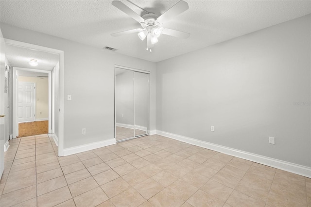 unfurnished bedroom featuring a textured ceiling, a closet, visible vents, and baseboards