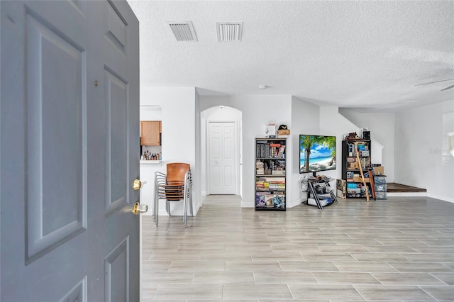 entrance foyer with visible vents, arched walkways, and a textured ceiling