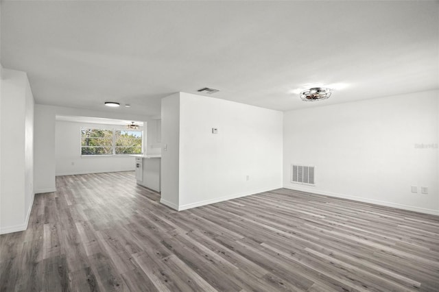 empty room featuring wood finished floors, visible vents, and baseboards