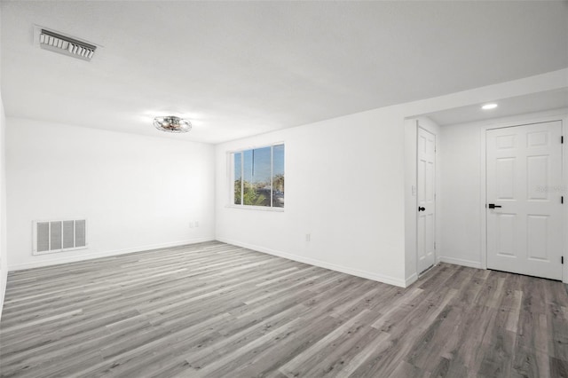 empty room featuring wood finished floors, visible vents, and baseboards