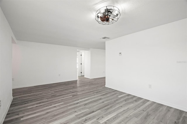 empty room featuring baseboards, visible vents, and wood finished floors