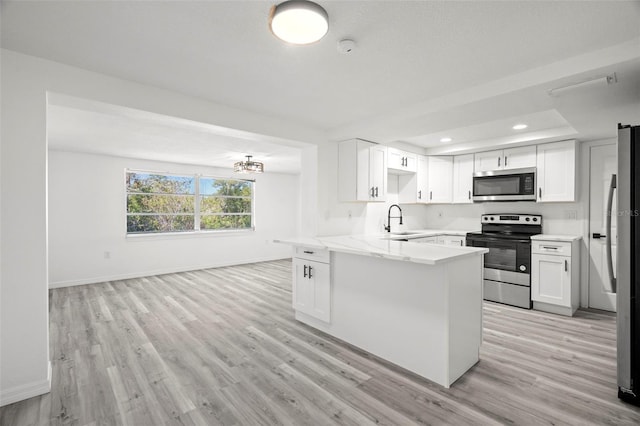 kitchen with stainless steel appliances, a sink, light wood-type flooring, a peninsula, and baseboards