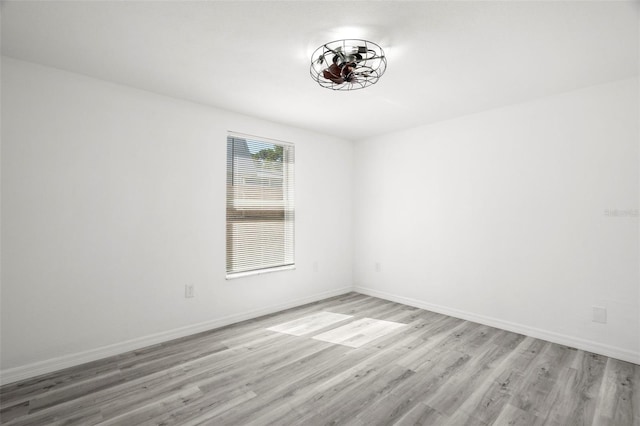 spare room featuring light wood-type flooring and baseboards