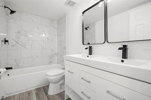 full bathroom with shower / bathtub combination, toilet, wood finished floors, visible vents, and double vanity