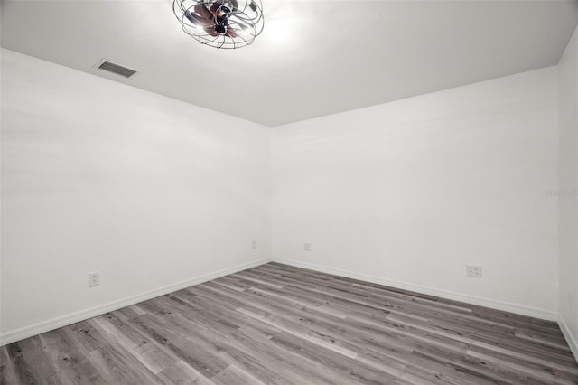 empty room featuring baseboards, visible vents, and wood finished floors