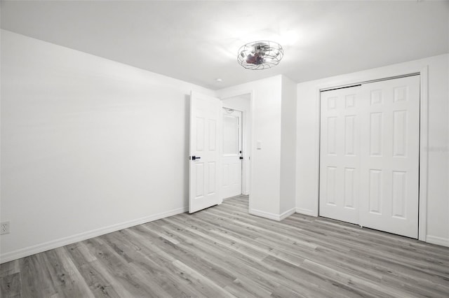 unfurnished bedroom with a closet, wood finished floors, and baseboards