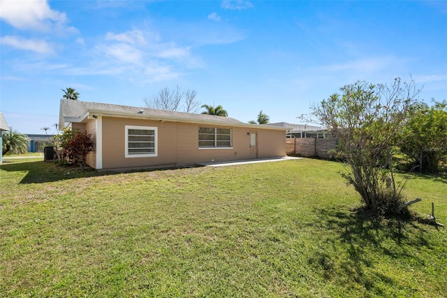 back of property with a patio, a yard, and fence