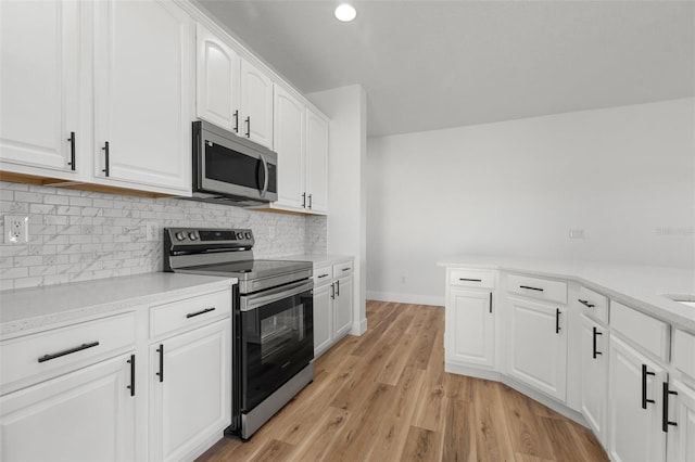 kitchen with stainless steel appliances, white cabinetry, baseboards, light wood-style floors, and tasteful backsplash