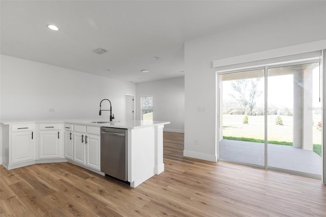 kitchen featuring stainless steel dishwasher, a sink, white cabinetry, and light wood-style floors