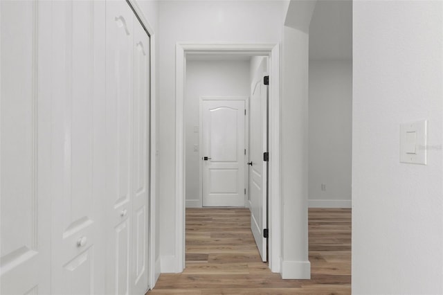 corridor with light wood-style floors and baseboards