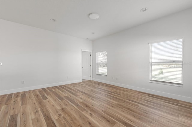 empty room featuring light wood-type flooring, baseboards, and recessed lighting