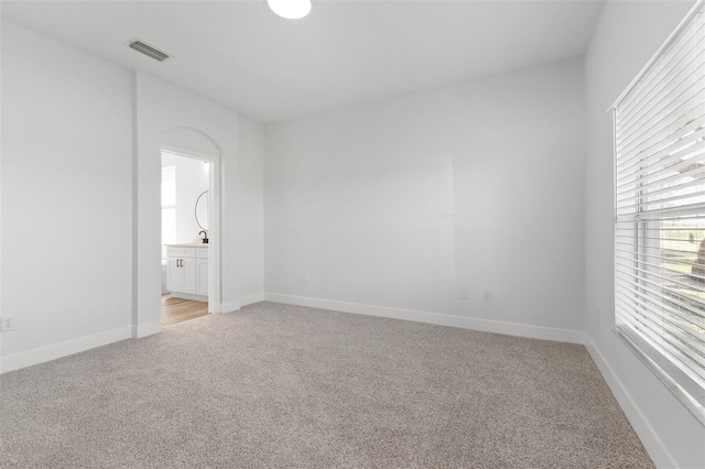 unfurnished bedroom featuring a sink, baseboards, connected bathroom, and light colored carpet