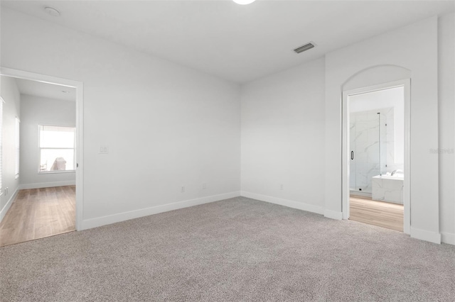 spare room with carpet flooring, visible vents, and baseboards