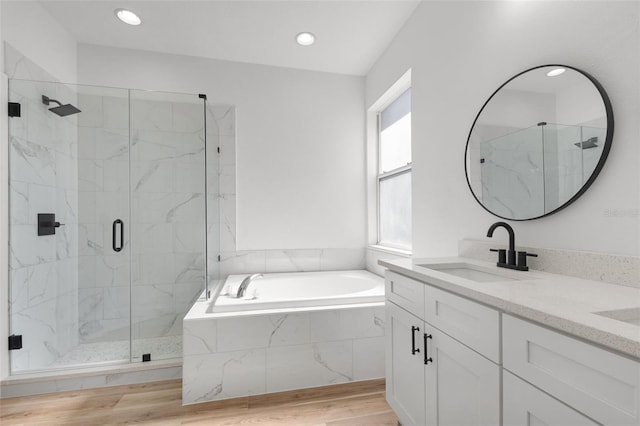 full bath with a marble finish shower, wood finished floors, vanity, a bath, and recessed lighting