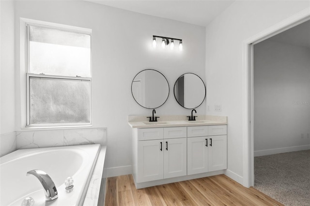 full bath featuring a bath, double vanity, baseboards, and a sink