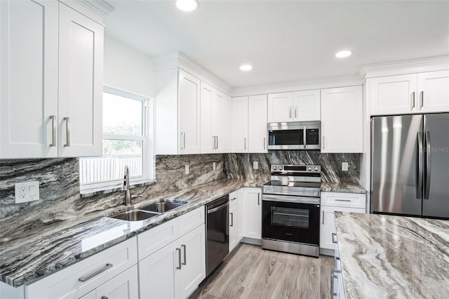 kitchen featuring light stone counters, appliances with stainless steel finishes, a sink, and white cabinetry