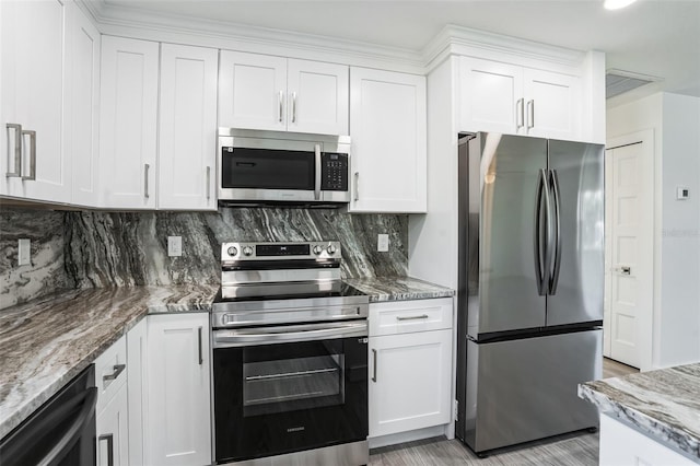 kitchen with stainless steel appliances, decorative backsplash, and white cabinets