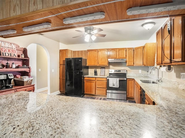 kitchen featuring a ceiling fan, a sink, light stone countertops, under cabinet range hood, and black appliances