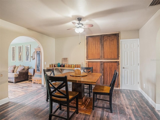 dining space featuring baseboards, visible vents, arched walkways, and wood finished floors