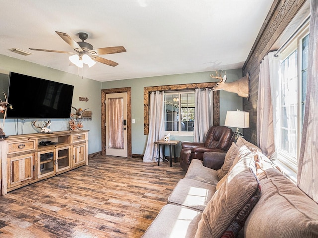 living room featuring baseboards, ceiling fan, visible vents, and wood finished floors