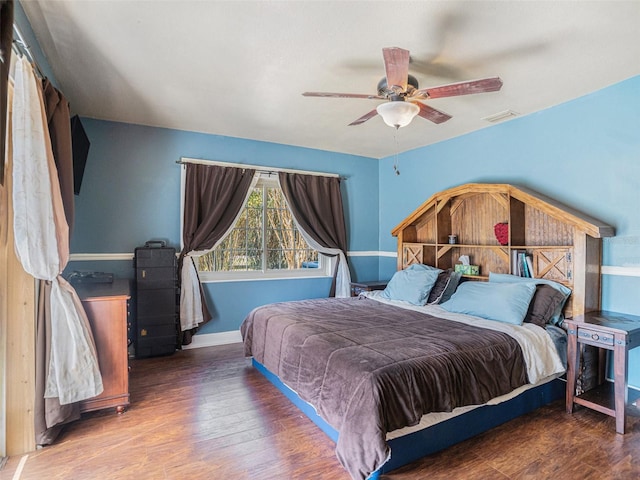 bedroom with a ceiling fan, wood finished floors, visible vents, and baseboards