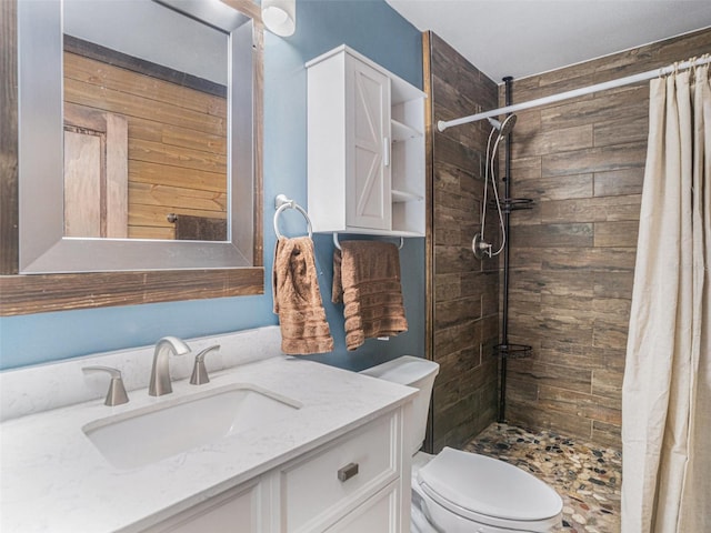 bathroom with tiled shower, vanity, and toilet