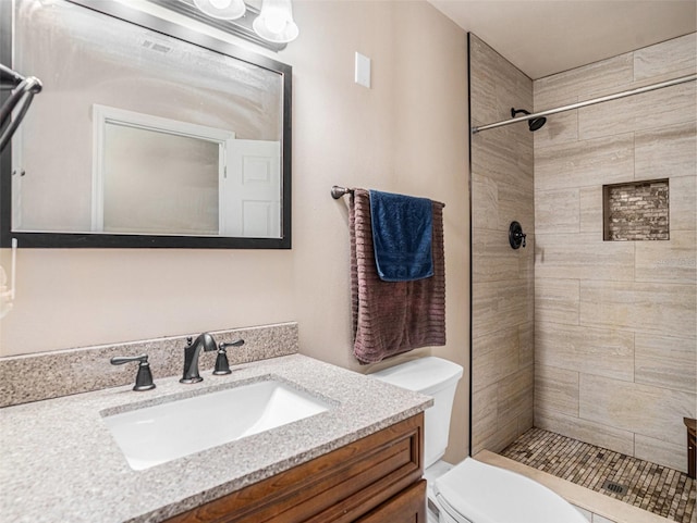 full bath with vanity, a tile shower, and toilet